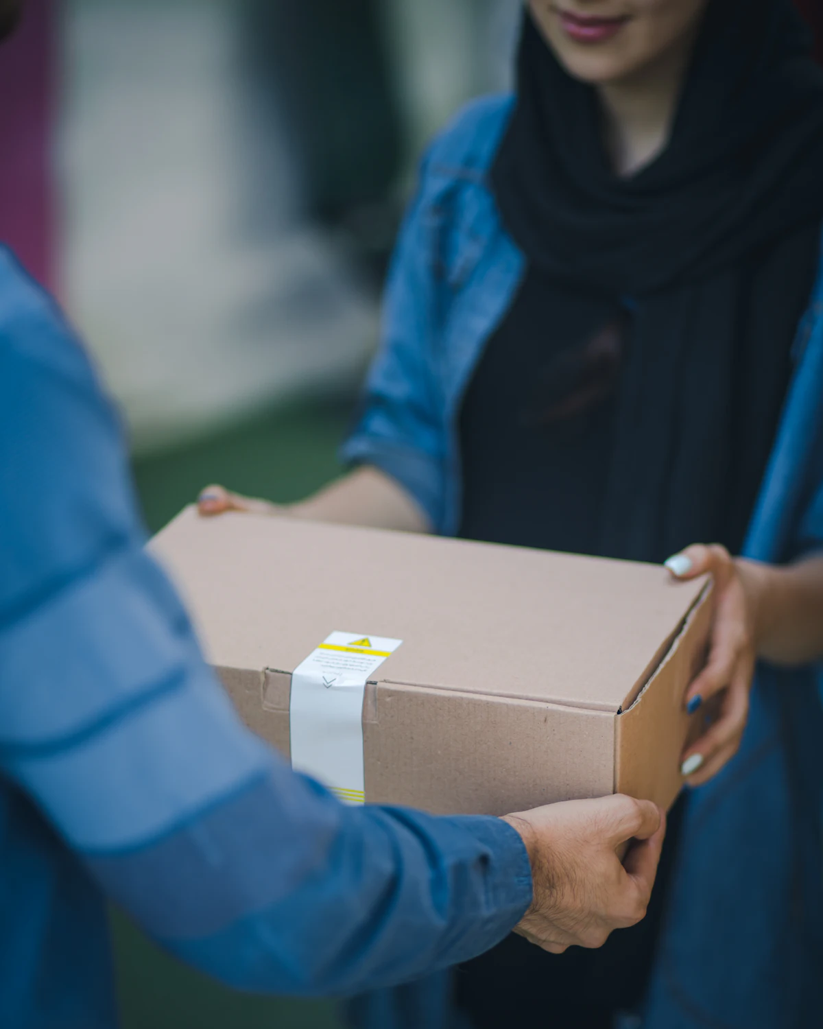 Hands passing a cardboard package from one person to another