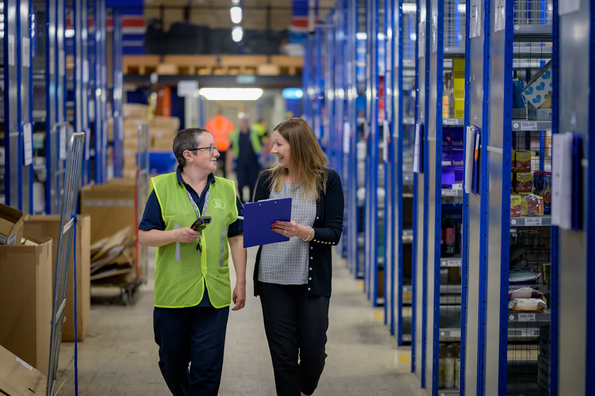 Team walking through a warehouse aisle with stocked shelves